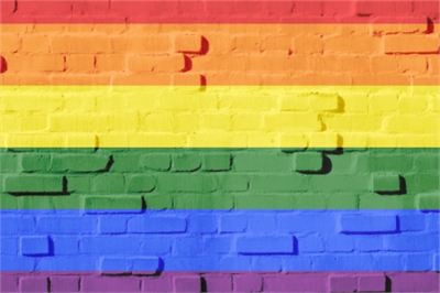 [ai] A brick wall painted with horizontal stripes in the colors of the rainbow: red, orange, yellow, green, blue, and purple.